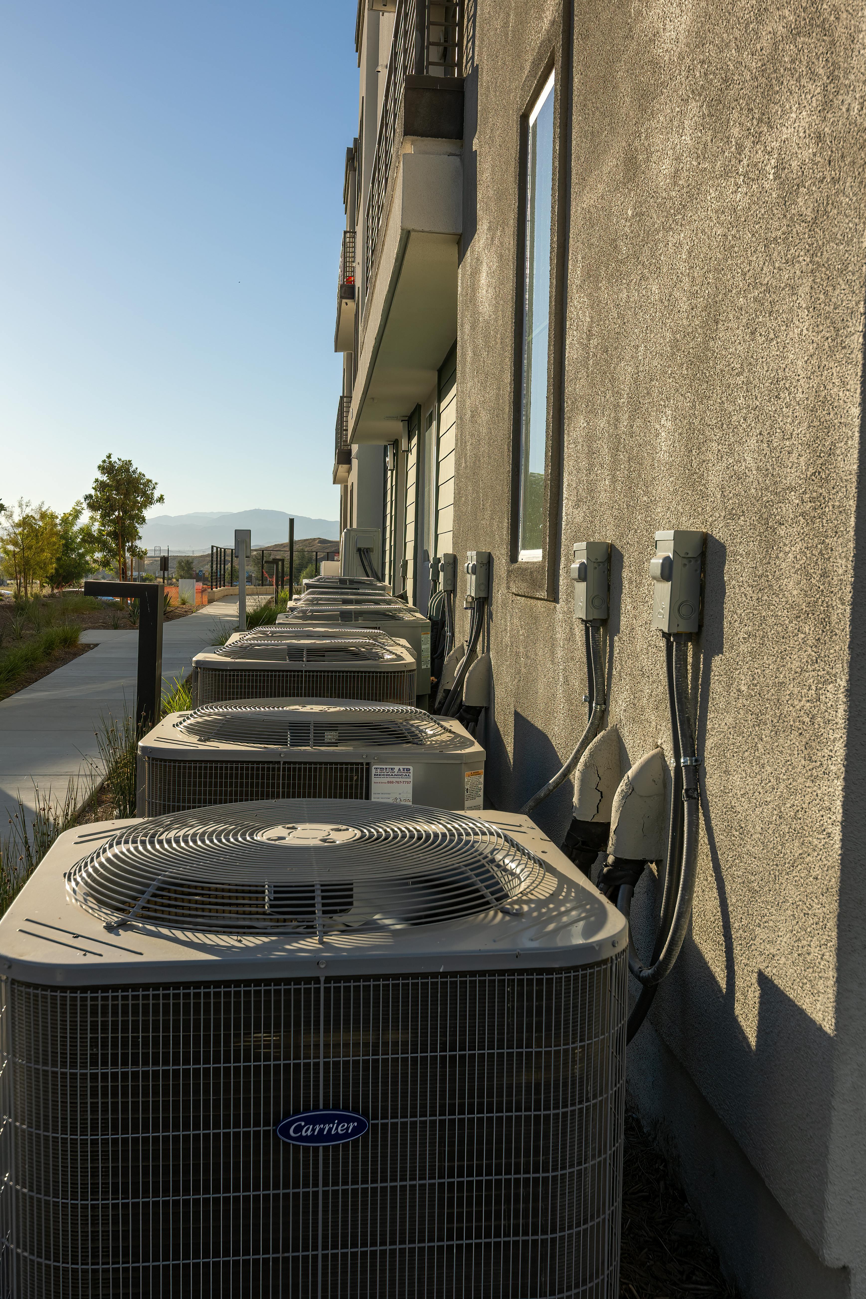 A row of Carrier air-conditioning condensers along a multi-unit residential building